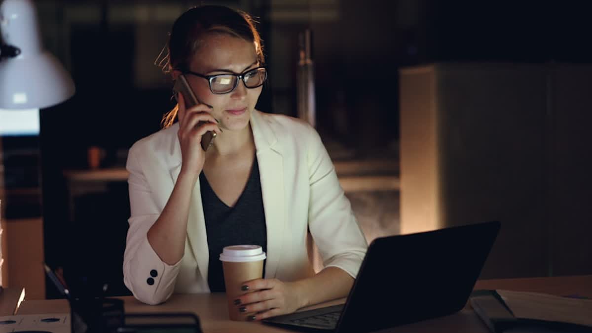 IT Support Escalation Ownership for Riverside Businesses illustration of Woman talking on phone at desk with laptop and coffee