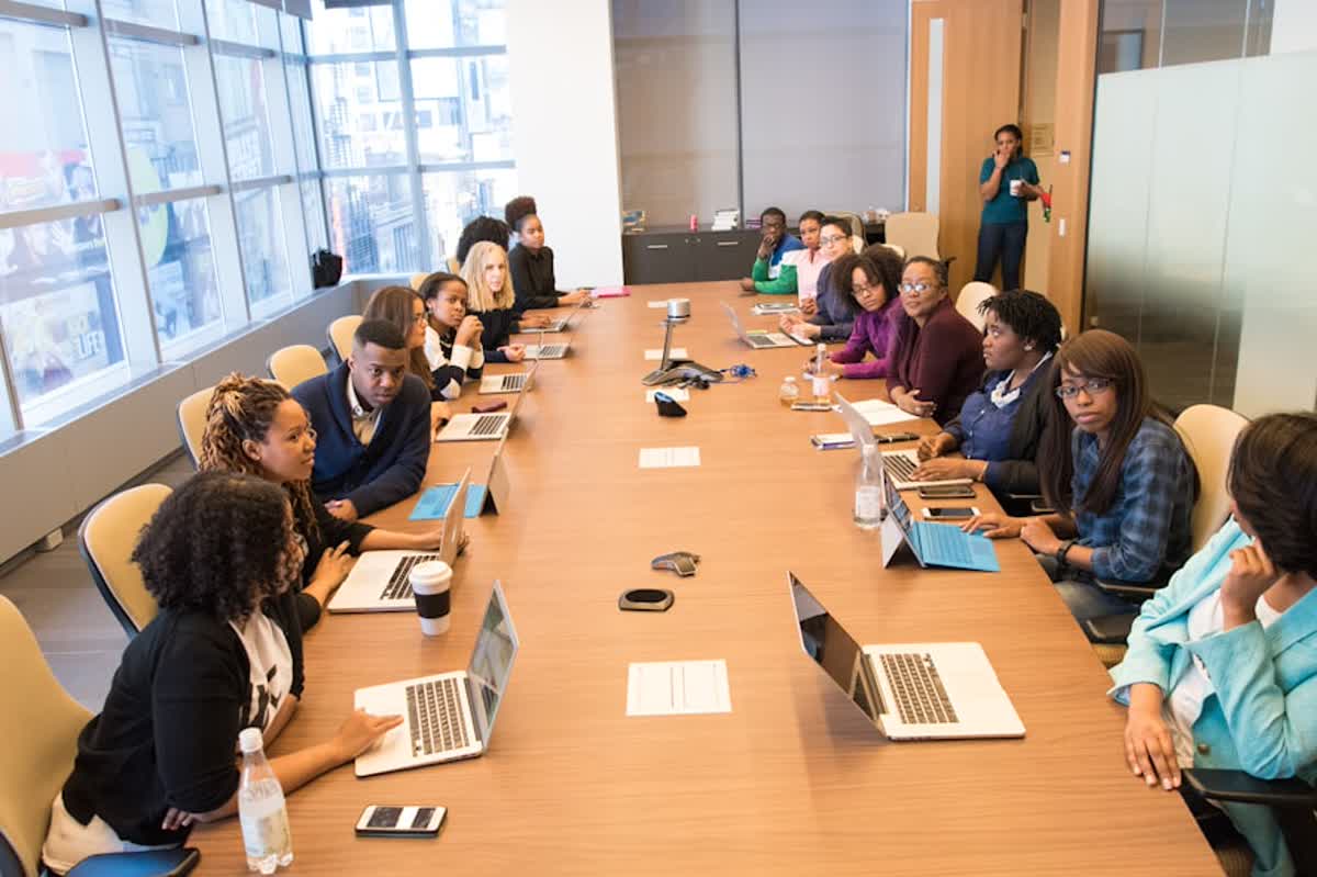Managed IT Vendor Coordination Checklist for Riverside Businesses illustration of people sitting beside rectangular brown table with laptops